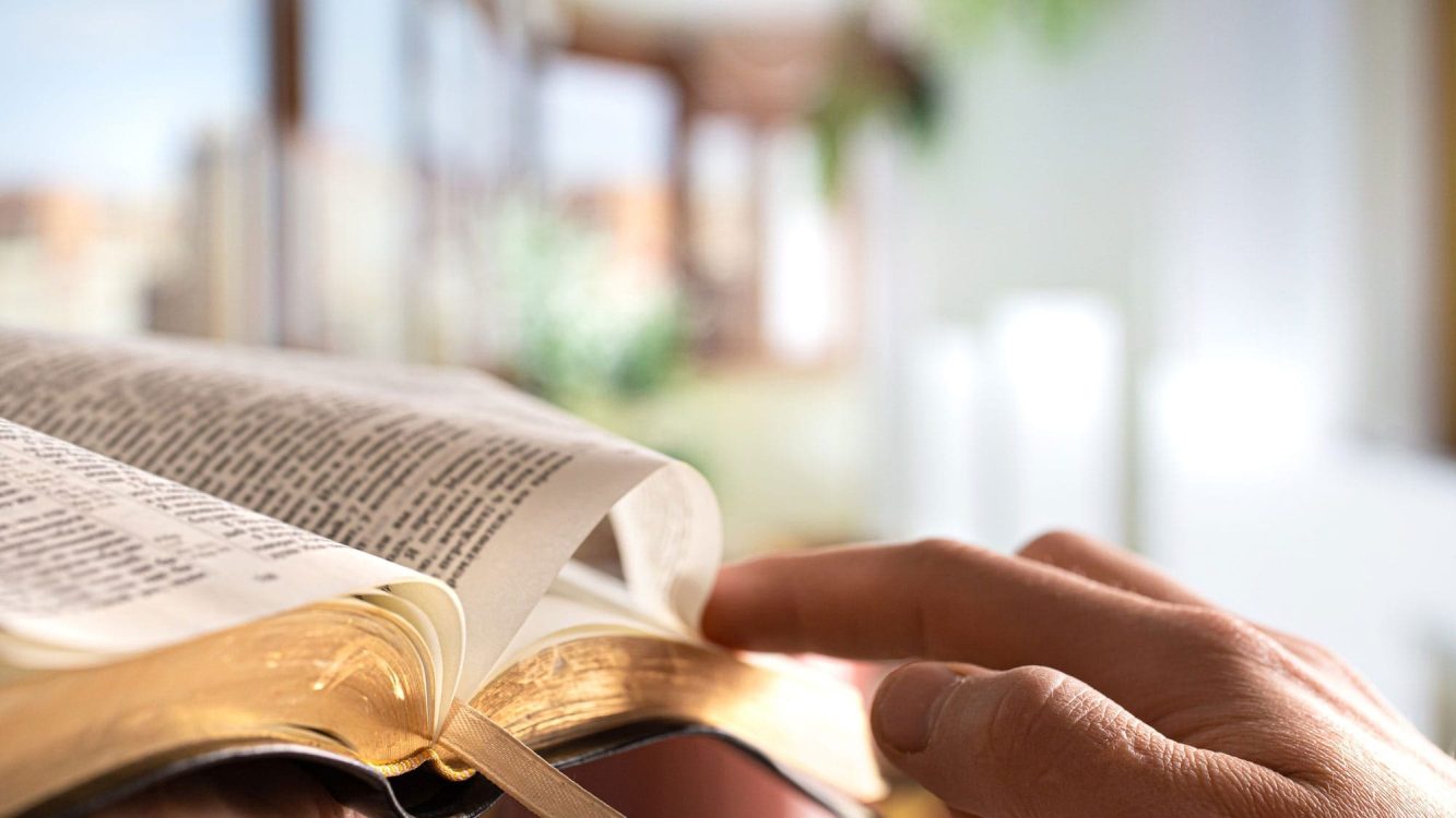 Hands turning pages of the Bible – symbolic image of studying God's Word from Paula White Ministries